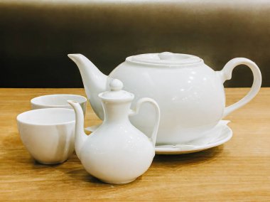 Ahşap bir masada beyaz porselen çaydanlık.