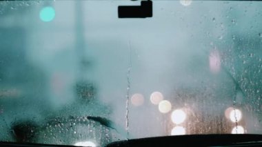 Arka camdaki yağmur damlaları ve arka plandaki sileceklerle temizleniyor.
