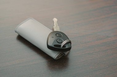 Kapı kilidi uzaktan kumandalı ve anahtarlığı ahşap bir masada olan modern bir araba anahtarı.