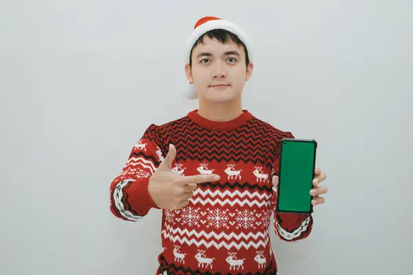 Asyalı Noel Baba elinde beyaz arka planda yeşil ekran akıllı telefon tutuyor. Tatil sezonunda promosyon malzemesi için uygun.