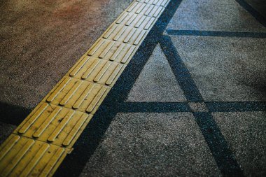 Colored concrete street sidewalk with yellow tactile lines for visually impaired people clipart