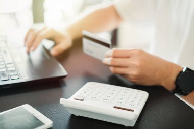 Kredi kartı tutan ve dizüstü bilgisayar kullanan adam ellerini kapat. İnternet mağazasında online alışveriş yapıyor. Banka hizmetleri ve güvenli ödeme bilgileri giriliyor.