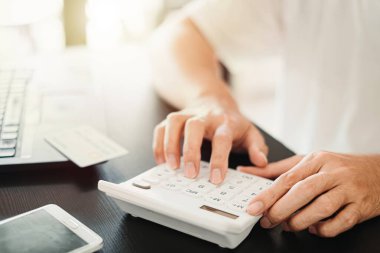 Kişisel finansman, bütçe veya muhasebe, bütçe yönetimi, aylık harcamalar, Bokeh geçmişi olan mali planlama hesaplamak için hesap makinesi ve dizüstü bilgisayar kullanarak adam elini kapat