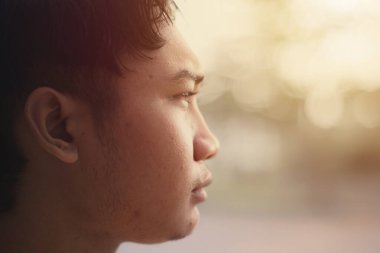 Güneydoğu Asyalı adamın yan profili Bokeh arka planına bakıyor. Yakın çekim..