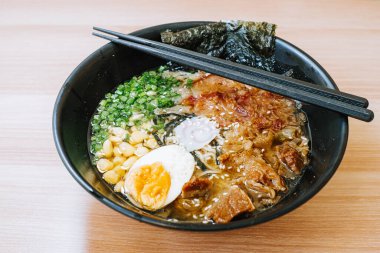 Mısır, pırasa, yarım yumurta, sığır eti, nori ve narutomaki soslu Japon eriştesi. Yemek çubukları siyah kasede. Japon geleneksel yemeği.