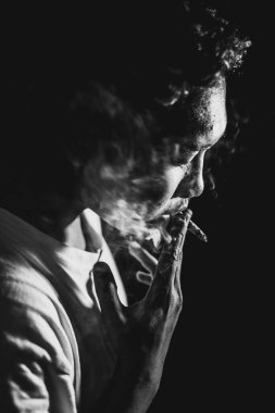 Güneydoğu Asyalı genç adam Bokeh 'le siyah beyaz sigara içiyor. Yakın plan güzel sanatlar..