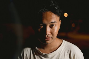 Genç Güneydoğu Asyalı adam kameraya bakıyor.