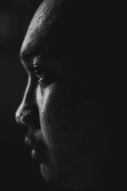 Geçmişi bulanık ifadesiz, sağ tarafa bakan Güneydoğu Asyalı bir adam. Yakın çekim ve vesikalık kare. Siyah beyaz moda fotoğrafçılığı.