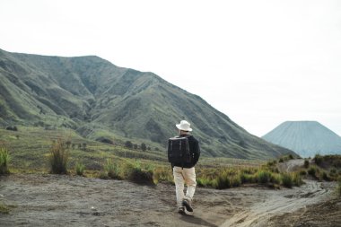 Doğu Java, Endonezya 'daki Bromo Dağı' nda tek başına yürüyen, şapka ve sırt çantası takan genç bir Güneydoğu Asyalı 'nın arka görüntüsü..