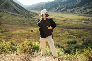 Doğu Cava, Endonezya 'daki Bromo Dağı' nın manzaralı vadisinde şapka ve sırt çantası takan genç bir Güneydoğu Asyalı..