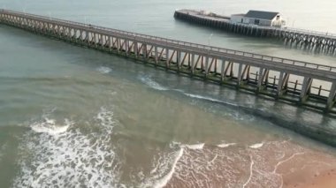 Güneş doğarken Blankenberge, Belçika 'daki sahil ve liman manzaralı, rıhtımın yanında dalgalar akıyor.