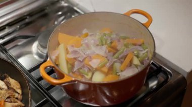 Taze patates, fasulye ve soğan, gaz sobasında, portakal kabında haşlanıyor.