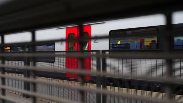 第二種客車が見える駅のフェンスの後に残る列車のパンニングショット — ストック動画