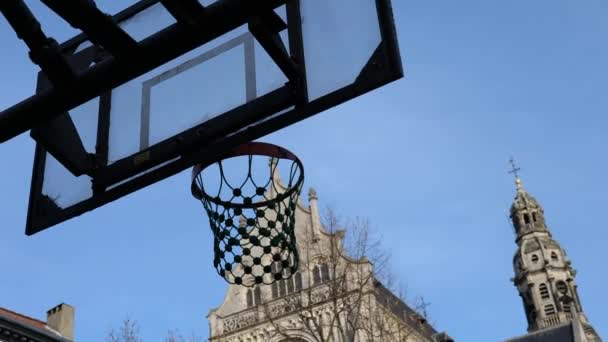 Basketbol Arka Planda Kiliseyle Eski Kasaba Meydanında Sepetin Içinde Vuruluyor — Stok video