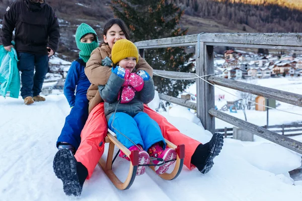 带着三个孩子的父亲带着木制雪橇在雪坡上走下去 — 图库照片