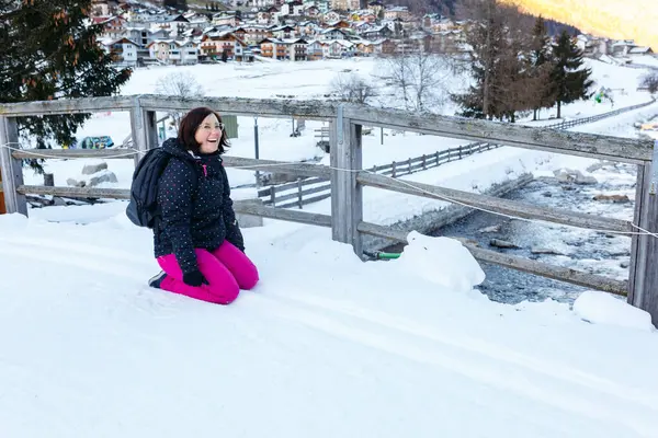 与孩子们玩耍后 穿着粉色滑雪裤的笑女人躺在雪地上 — 图库照片