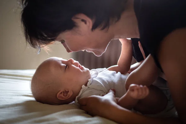 stock image mother with dark hair watching her newborn baby laying on the bad