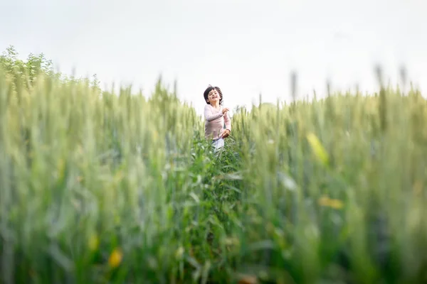 stock image smiling happy girl with short hair in pink top run happily in green wheat field