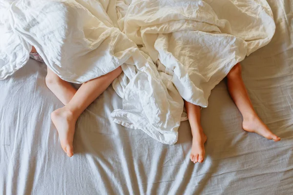 Két Kisgyermek Lába Akik Fehér Ágynemű Lepedő Alatt Alszanak — Stock Fotó