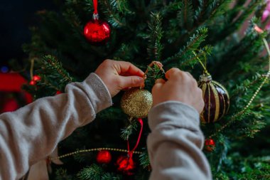 Kırmızı Noel ağacı süslemesi ile çocuk ellerine yakın dur ve ağaca as.