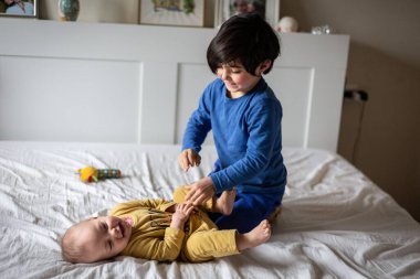 Pijamalı iki kız kardeş, ebeveyn yatağında oynuyorlar.