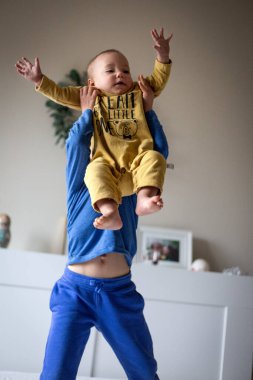 İkisi yatakta duruyor. Mavi ve sarı elbiseli çocuklar oynaşıyor, birbirlerine sarılıyorlar.