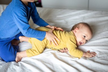 Pijamalı iki küçük kız kardeş ebeveynin yatağında oynuyorlar.