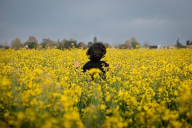 Koyu renk elbiseli, sarı çiçekli, kaçan çocuğun arka camı.