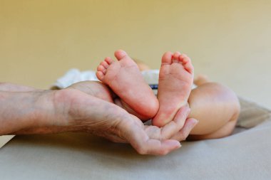 Yaşlılar tarafından tutulan bebeğin ayaklarının yakın görüntüsü