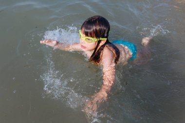 upper view of small child learning swimming on a sunny day