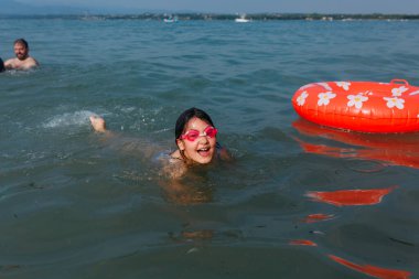 Güneşli bir günde şişme halkanın yanında yüzmeyi öğrenen mutlu bir çocuğun üst görünümü