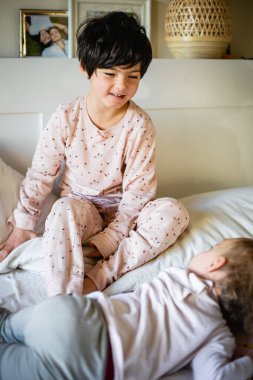 Ebeveynlerin yatağında oynayan iki küçük çocuğun portresi.