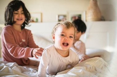 Yatak odasında oynayan üç küçük kız kardeş.