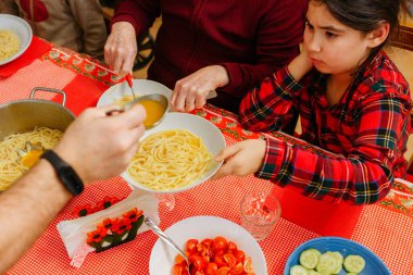 Noel masasında oturan bir çocuğun aile yemeğinde ebeveynin servis edeceği yemekleri beklemesi.