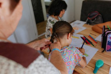 Büyükannenin el örgüsü, küçük torunun saçı, çizim yaparken yakın plan görüntüsü.