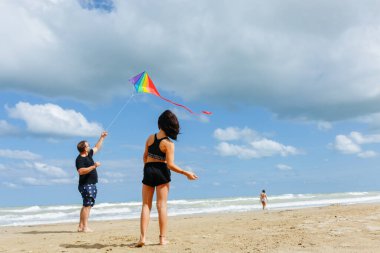 Sahilde uçurtma uçuran bir adamla bir çocuğun geniş açılı görüntüsü