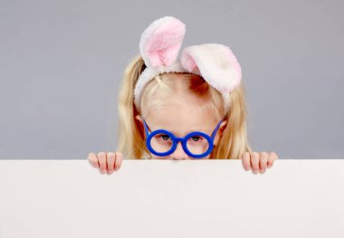 Paskalya yumurtaları ve tavşan kulaklı sevimli kız yazıtlar için beyaz bir çarşaf tutuyor, boş alan, paskalya kompozisyonu, dini bayram kavramı, bahar havası, izole edilmiş.