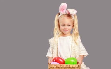 Tavşan kulaklı, sepetli, paskalya yumurtalı tatlı küçük kız. Paskalya tavşanı kulaklı çocuk