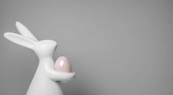 Керамический Пасхальный Кролик Держит Розовое Яйцо Лапах Фигура Белого Кролика — стоковое фото