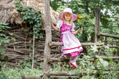 Güzel, küçük mutlu bir kız elbise içinde ve doğada bir buket sarı çiçekle. Çocuk dışarıda. Parkta yürüyen bir kız..