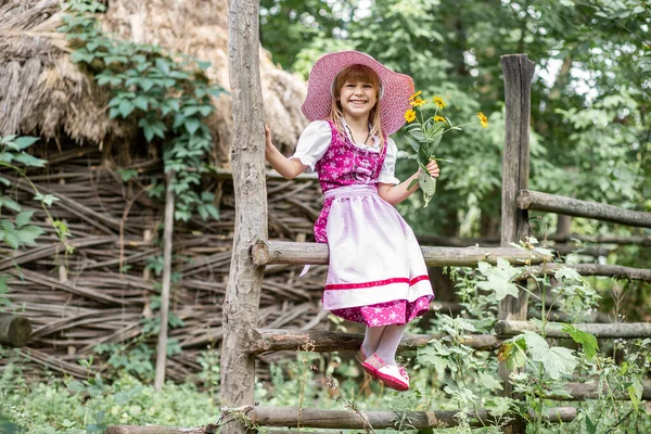 ドレスの美しい小さな幸せな女の子と村の自然の中で黄色の花の花束と 屋外の子供 公園を散歩中の女の子 — ストック写真