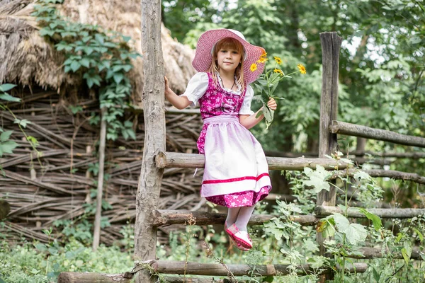 stock image Beautiful little happy girl in a dress and with a bouquet of yellow flowers in nature in the village. Child outdoors. Girl on a walk in the park.