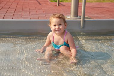 Mavi mayolu bir kız çocuk havuzunda mayo giyip oynuyor. Çocuk yüzmeyi öğreniyor. Yaz aktif açık hava oyunları.