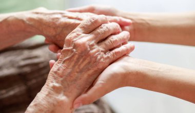 Eller yakın çekim. Yaşlı bir kadının elleri ve küçük bir çocuğun elleri birbirine dokunur. Nazikçe dokun. Yaşlı neslin bakımı. El sıkışarak sevginin ifadesi.