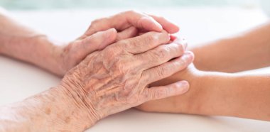 Eller yakın çekim. Yaşlı bir kadının elleri ve küçük bir çocuğun elleri birbirine dokunur. Nazikçe dokun. Yaşlı neslin bakımı. El sıkışarak sevginin ifadesi.