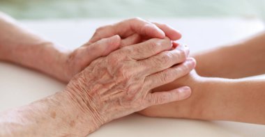 Eller yakın çekim. Yaşlı bir kadının elleri ve küçük bir çocuğun elleri birbirine dokunur. Nazikçe dokun. Yaşlı neslin bakımı. El sıkışarak sevginin ifadesi.