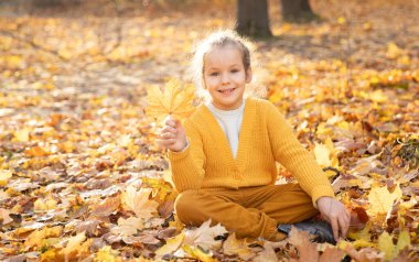 Sonbaharda güzel bir kızın portresi. Ağaçlarda turuncu ve sarı yapraklar. Ekim. Çocuklarla parkta bir yürüyüş..
