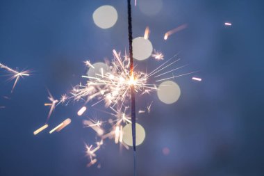 Yeni yıl arkaplanındaki havai fişeklerden yapılmış güzel kıvılcımlar, mavi arka plan, Noel havası, parıltı, tatil geçmişi.