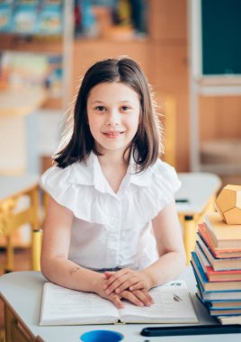 Okula dönecek olursak, birinci sınıf öğrencisi bir kız ders sırasında bir okul masasında otururken kitap okur. Bir liseli kız ders kitaplarını kullanarak ders çalışıyor. Okul malzemeleri bir çocuğun masasında..