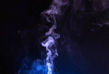 Smoky tendrils rise gently into the air, twisting and swirling in mesmerizing patterns. The dark backdrop enhances the delicate, wispy forms, offering a moment of tranquil beauty.